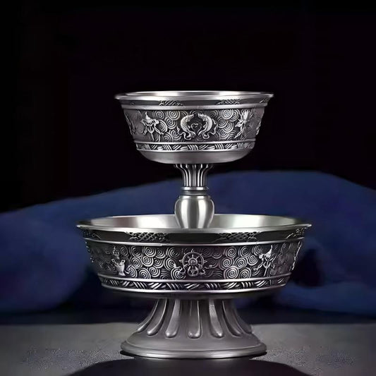 Tibetan Buddhist sacrificial implements culture: Close-up of a hand-engraved pewter chalice showcasing traditional Buddhist sacrificial items art and intricate Ashtamangala patterns.