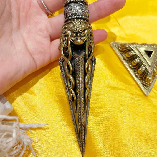 Handcrafted brass Phurba Vajra dagger with base, rooted in Tibetan Buddhist ritual implements culture and Buddhist ritual implements art, symbolizing protection and the subjugation of negative energies.