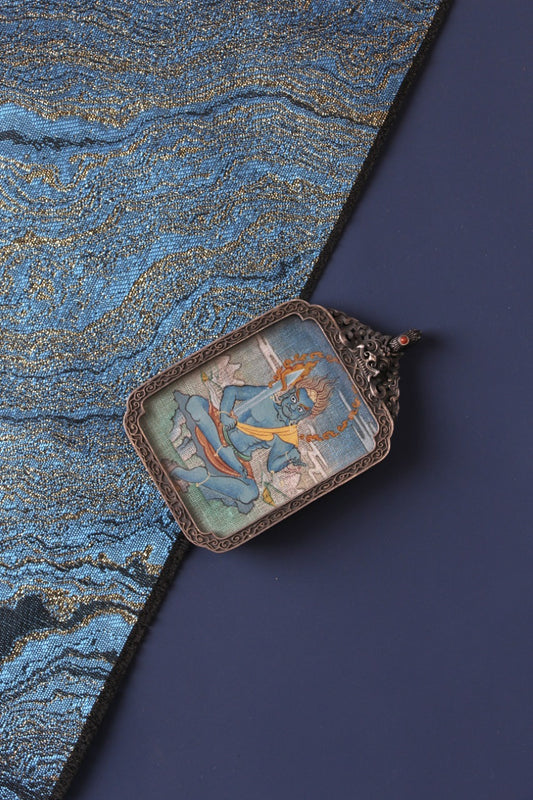 Tibetan Buddhist thangka pendant depicting Acala, the Immovable Wisdom King, symbolizing protection, determination, and enlightened power.