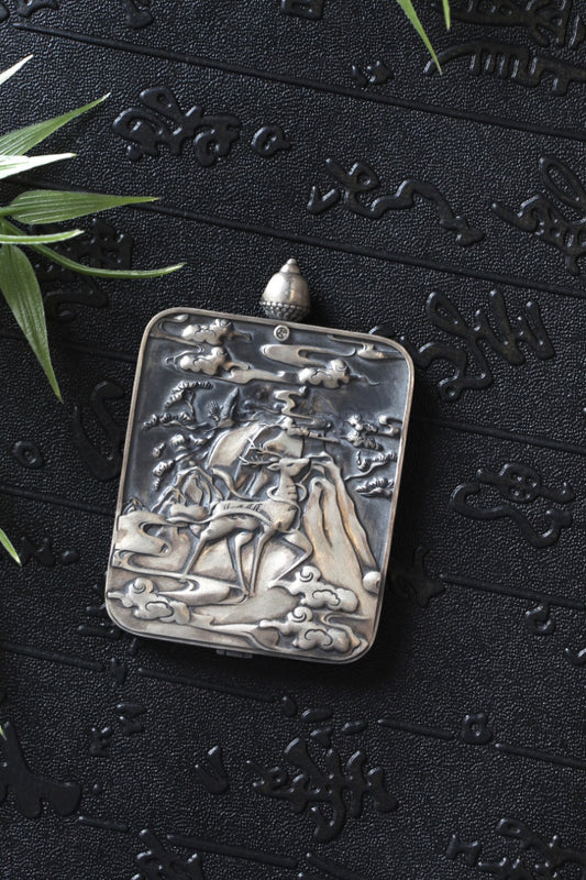 Tibetan Buddhist thangka pendant depicting Black Jambhala, the wealth protector deity, symbolizing prosperity, protection, and abundance.