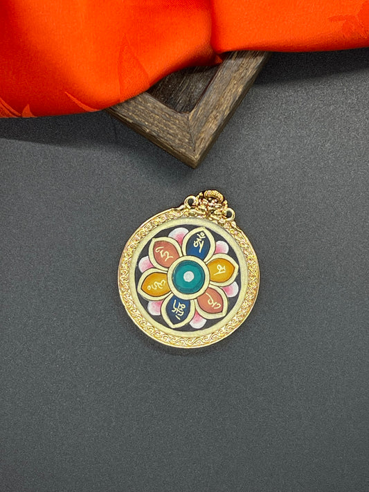 A 3.5cm hand-painted Rekong Lotus Six Syllables (莲花六字真言) pendant featuring the Om Mani Padme Hum mantra in gold on a mineral-pigment lotus, representing merit and protection in Buddhist tradition.
