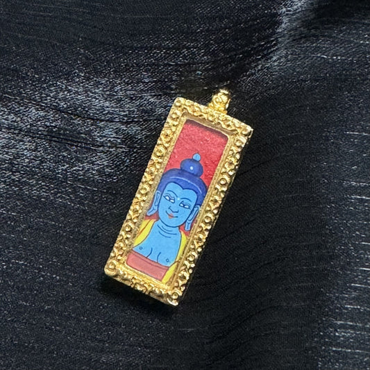 The Rebgong Buddha Head Medicine Buddha Thangka pendant displayed as a sacred amulet for healing and longevity, embodying Tibetan Buddhist tradition.