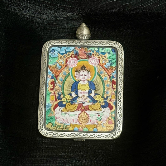 The Menri Vairochana Thangka pendant displayed as a sacred amulet for wisdom and success, embodying the cosmic light of Tibetan Buddhist tradition.