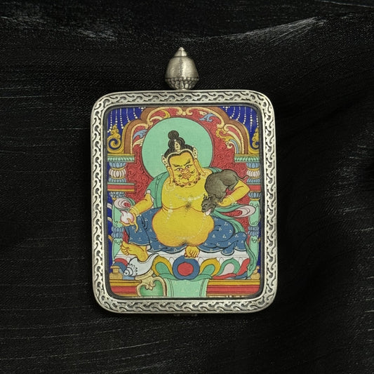 The Chigung Yellow Jambhala Thangka pendant displayed as a sacred amulet for wealth and merit, embodying the king of wealth deities in Tibetan Buddhist tradition.
