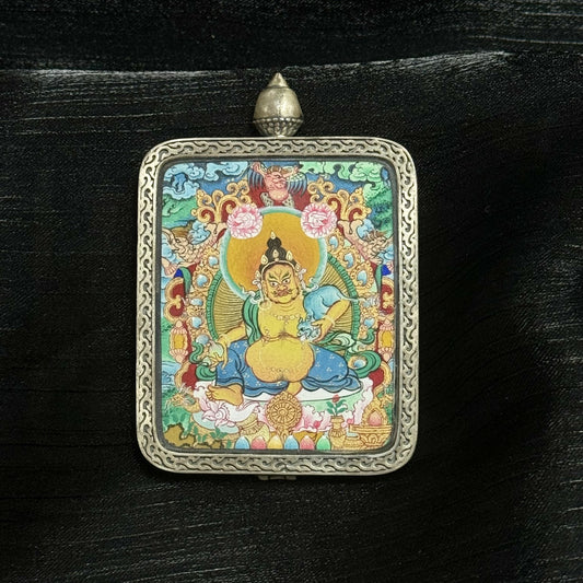 The Menri Yellow Jambhala Thangka pendant displayed as a sacred amulet for fortune and abundance, embodying the wealth blessings of Tibetan Buddhist tradition.