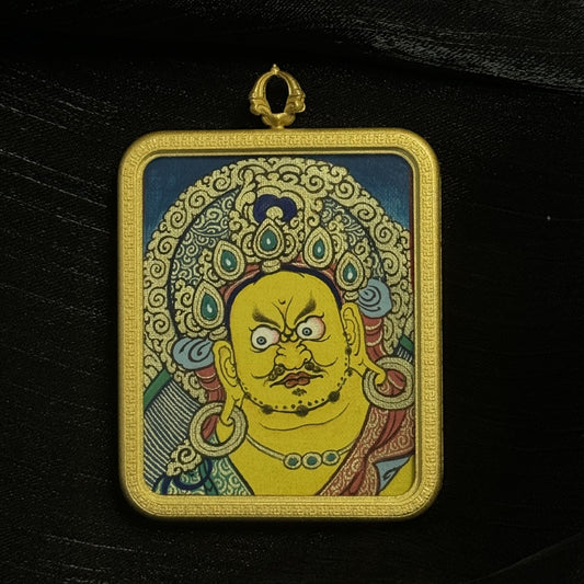The Rekong Yellow Jambhala Thangka pendant displayed as a sacred amulet for wealth, merit and blessing, embodying Tibetan Buddhist tradition.