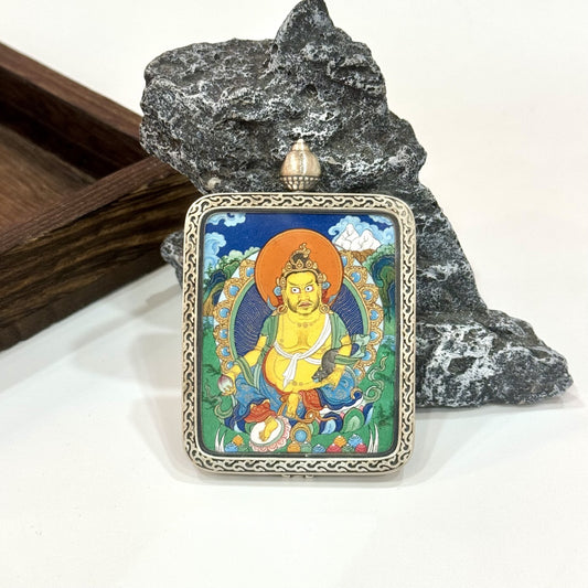 The Tibet Miansa Yellow Jambhala Thangka pendant displayed as a sacred amulet for wealth and auspicious fortune, embodying Tibetan Buddhist tradition.