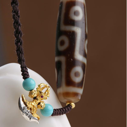Handcrafted Tibetan Buddhist Nine-Eyed Dzi pendant with turquoise and silver accents.