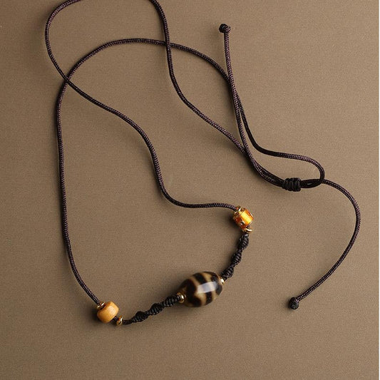 Tibetan Buddhist double tiger tooth Dzi bead necklace with bone and copper elements, featuring intricate Thangka painting details.