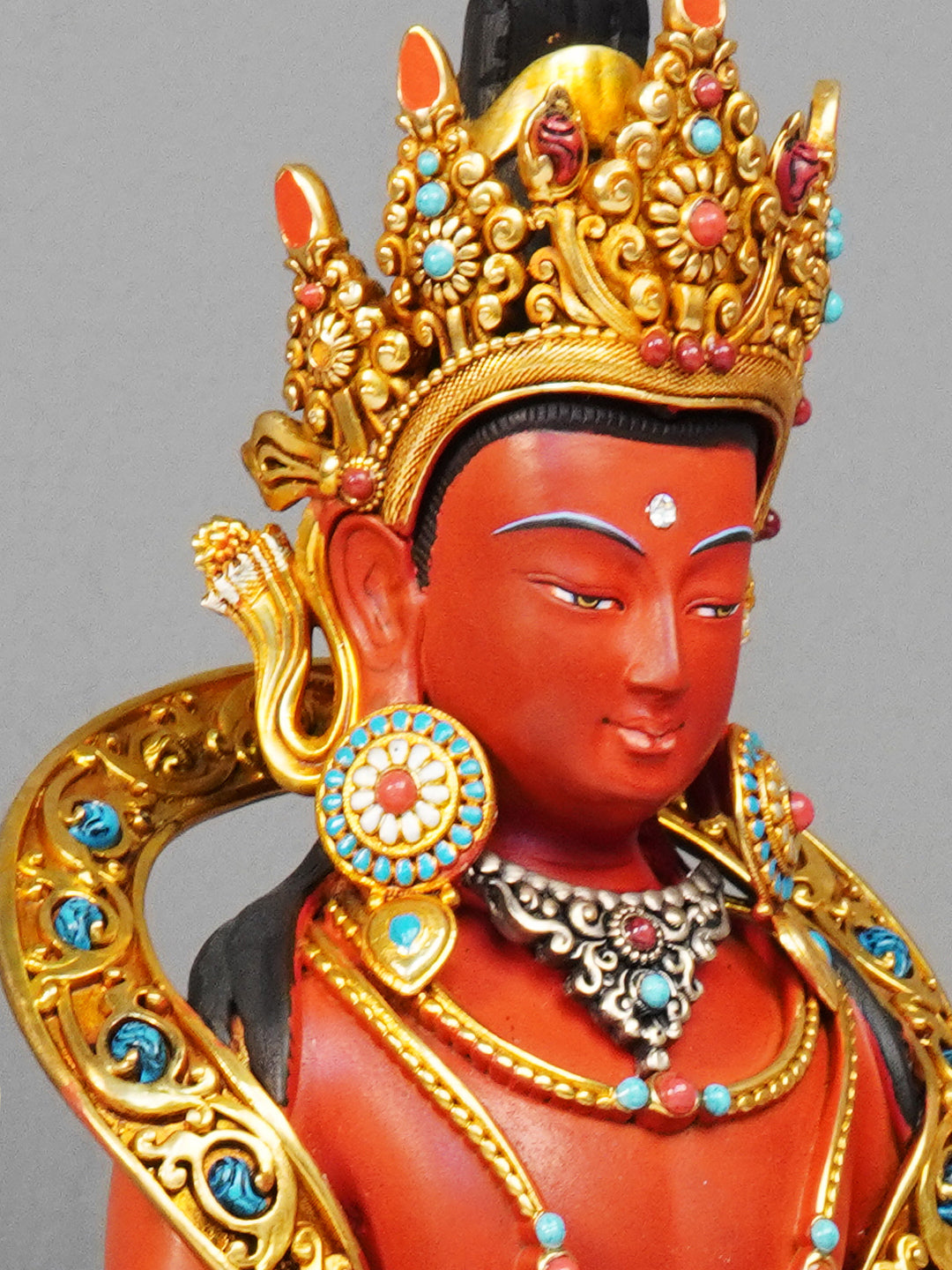Yellow brass Long Life Buddha statue with gilded features and mineral pigment painting, reflecting Tibetan Buddhist artistic tradition.