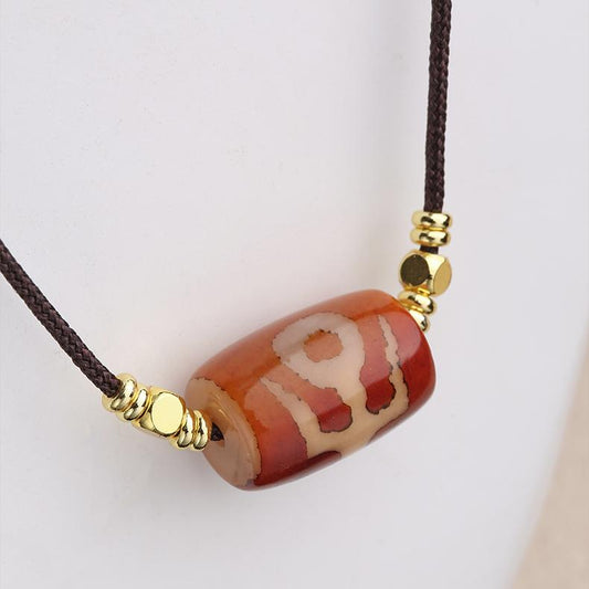 Close-up of a genuine red agate bead with a blue glass Nobleman Dzi pendant in Tibetan style.