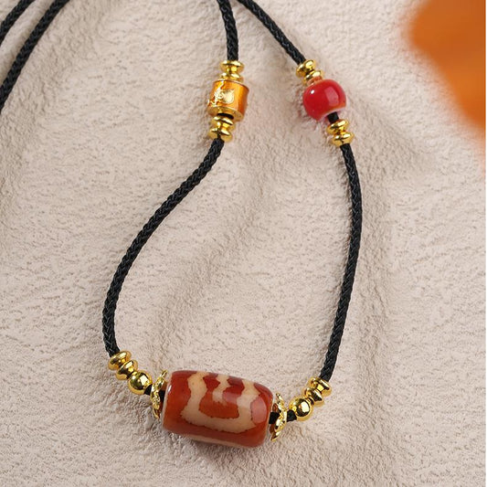 Tibetan Buddhist Garuda amulet necklace made of red agate, brass, and glass, featuring sacred thangka motifs that represent strength, wisdom, and spiritual protection.