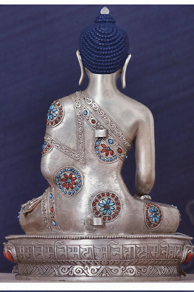Sacred Tibetan-buddhist Shakyamuni statue, handmade in silver with mineral pigments, showcasing Tibetan Buddha art tradition.
