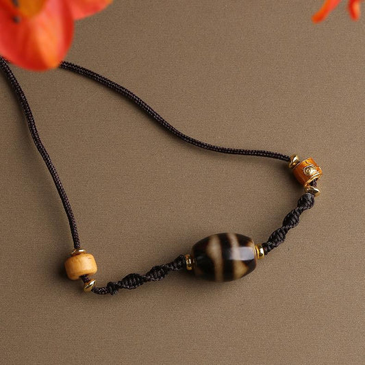 Tibetan Buddhist Dzi bead necklace with double tiger teeth, crafted with bone and copper, showcasing Thangka art design.