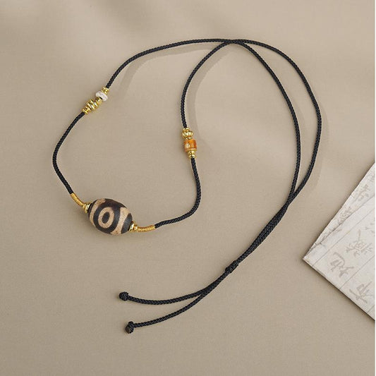 Handmade Tibetan Buddhist three-eye agate pendant with copper and glass details, inspired by traditional Tibetan thangka art for spiritual energy.