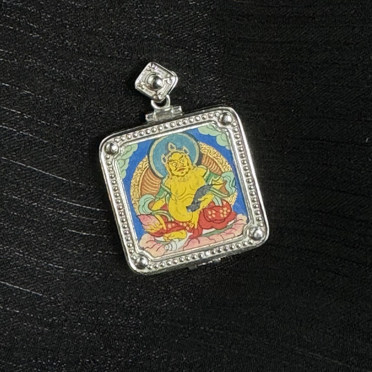  Detailed view of the 925 silver-plated casing for the Yellow Jambhala Thangka pendant, symbolizing protection and elegance in Tibetan Buddhist tradition.

