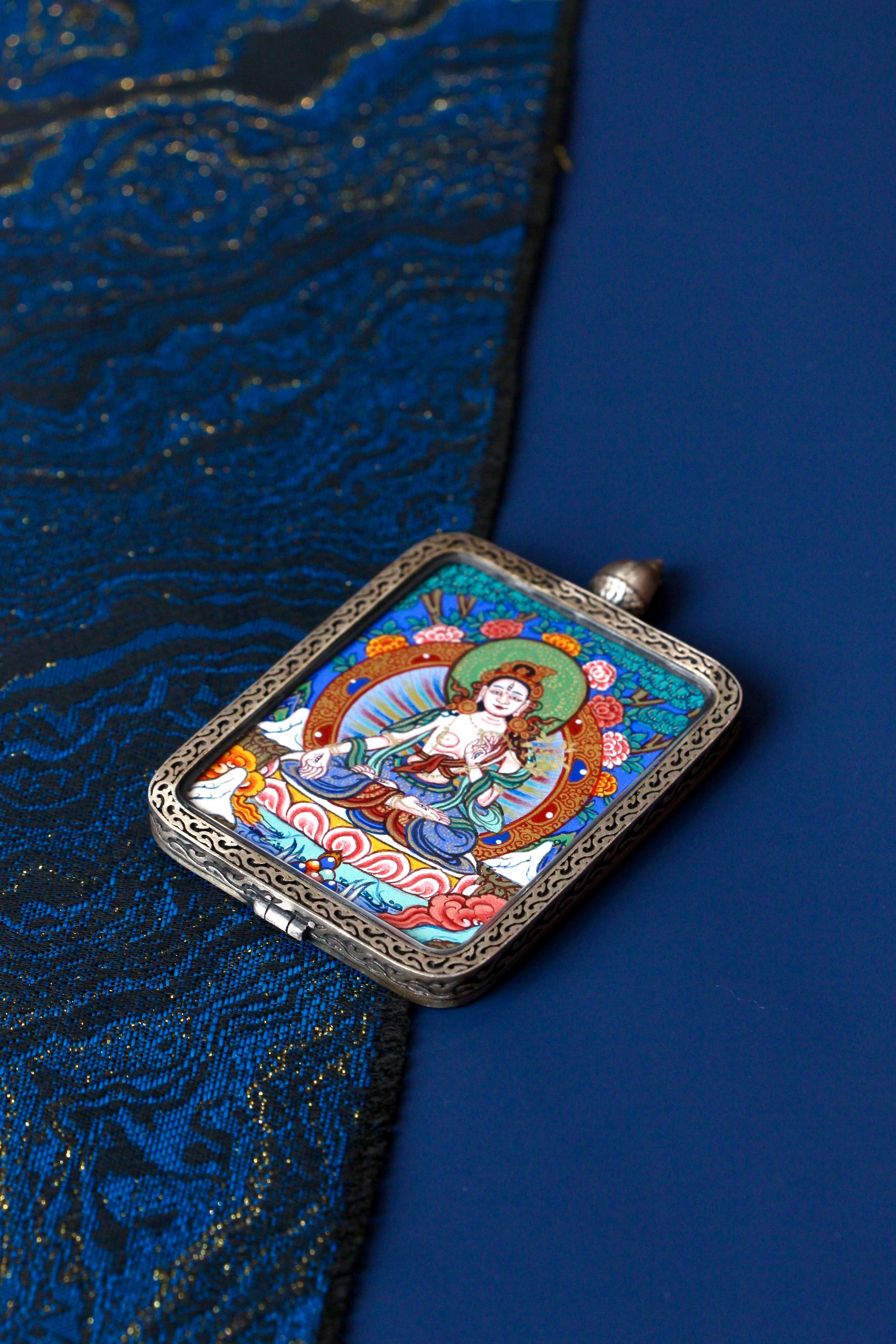 Macro view of a miniature White Tara Thangka showing the seven eyes of compassion and natural mineral pigments used in Regong artistry.