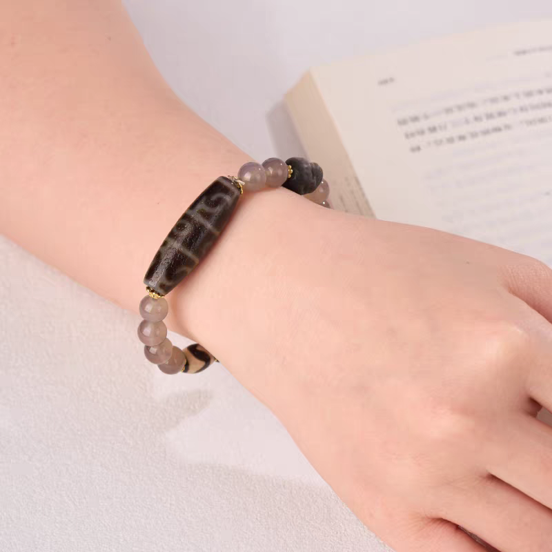 Handcrafted jewelry art bracelet featuring sacred lotus Dzi beads with dragon scale texture, representing power and wisdom.