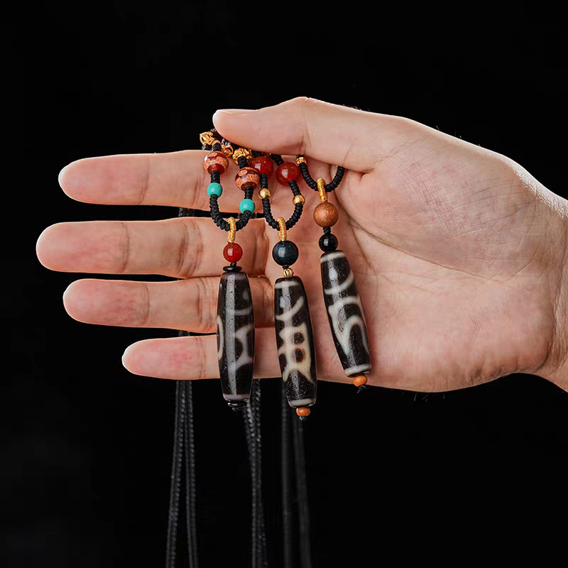 Handmade Dzi pendant with traditional Tibetan totems, showcasing jewelry art and Tibetan Buddhist Jewelry Culture. Purely handcrafted.