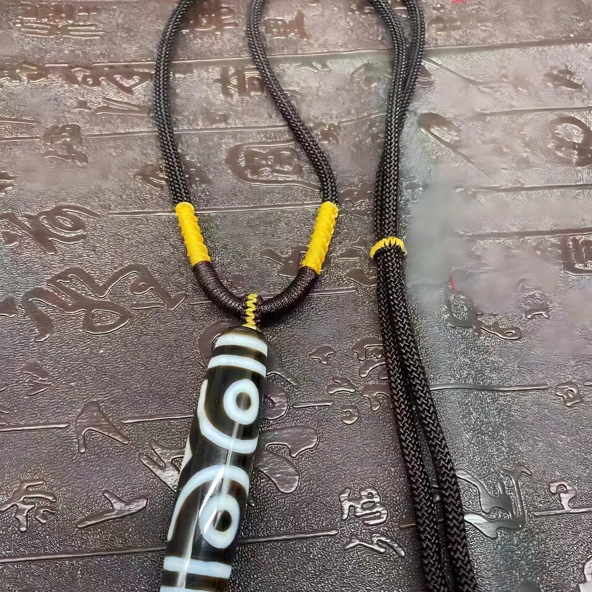 Handcrafted Nine-Eye Dzi bead pendant in ethnic Tibetan style, a jewelry art piece for protection, luck, and spiritual well-being.