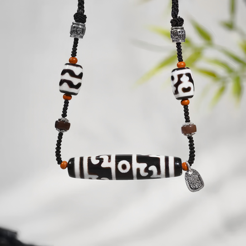 Handcrafted jewelry art clavicle necklace featuring a sacred Lotus Guru Dzi with black and white agate beads.