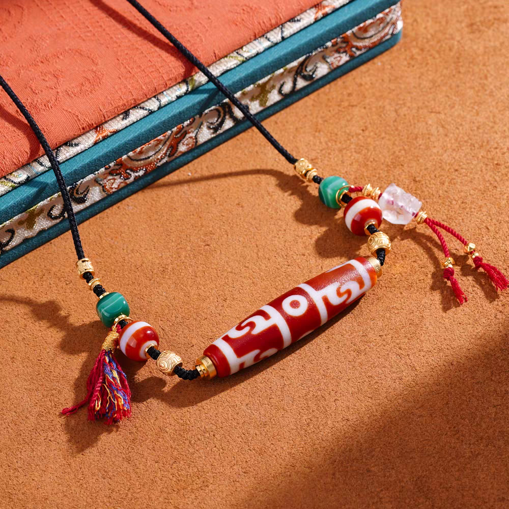 Handcrafted jewelry art clavicle necklace featuring sacred red meat Dzi beads, representing power and wisdom.
