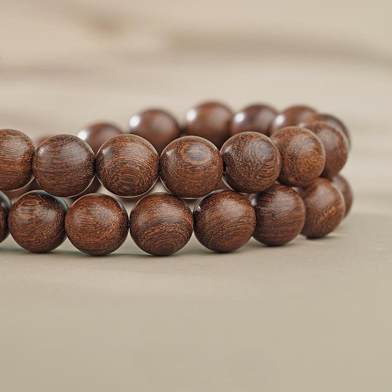 Close-up of the Eternal Ease bracelet's golden sandalwood beads. Highlights the pure hand-painted details, where natural wood grain complements exquisite patterns, making each bead a unique piece of jewelry art.