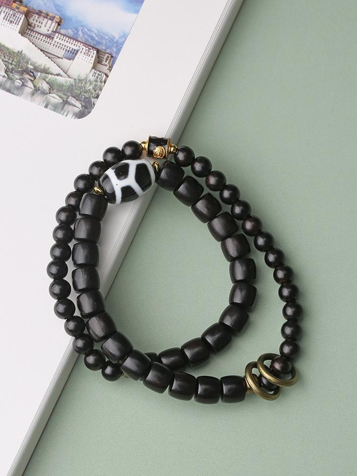 Tibetan Buddhist Jewelry Culture presents a Black Sandalwood and Agate bracelet adorned with sacred geometry designs. This hand-painted jewelry art piece symbolizes harmony and protection for the wearer.