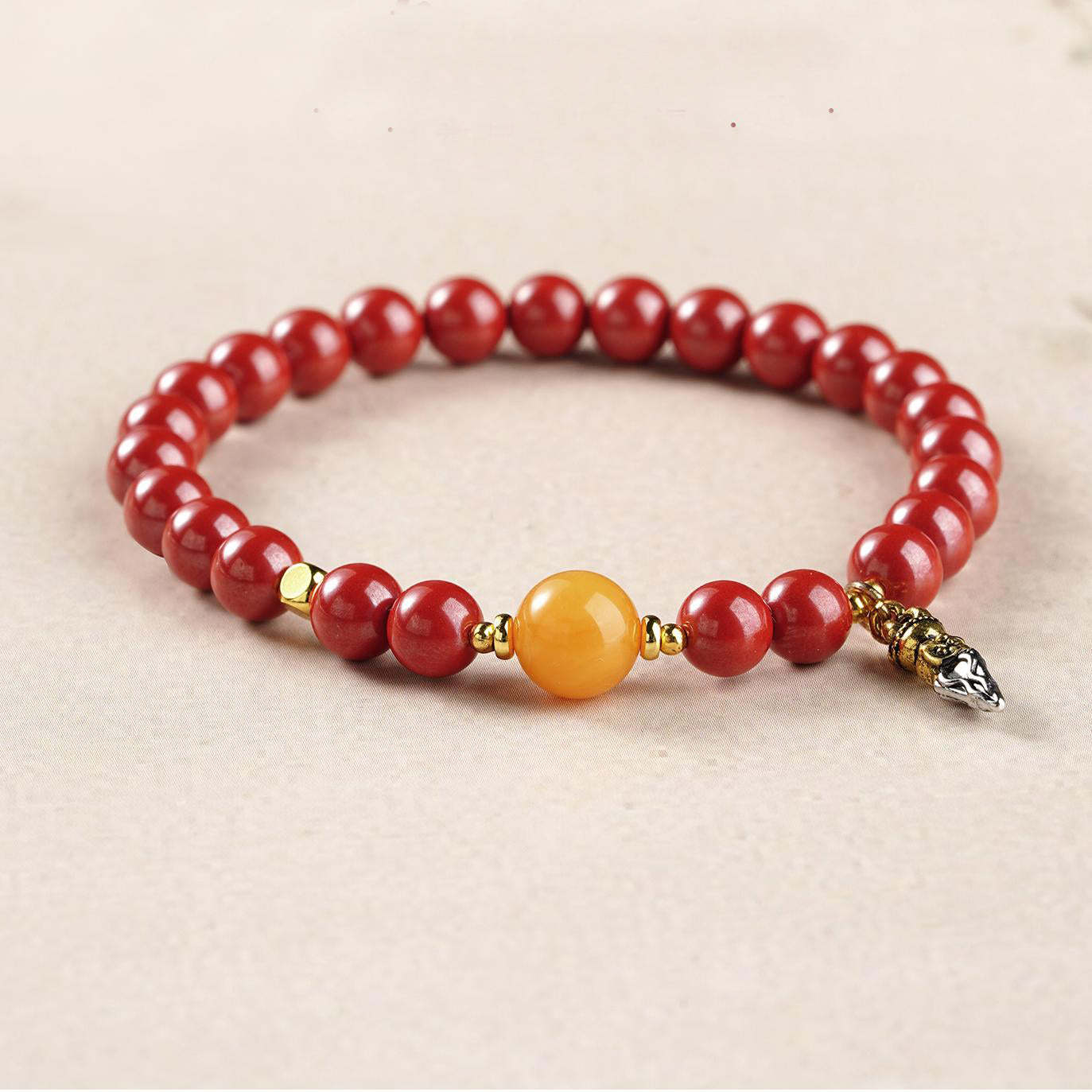 Artisanal Cinnabar and Amber beads in Tibetan Buddhist jewelry tradition, meticulously hand-painted with prosperity symbols.
