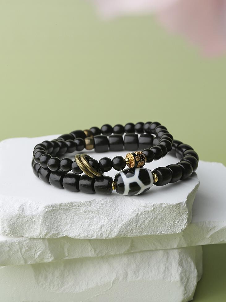 Close-up of a multi-row Black Sandalwood bracelet from Tibetan Buddhist Jewelry Culture, featuring intricate hand-painted patterns on agate beads. This unique piece of jewelry art is perfect for meditation and spiritual practice.