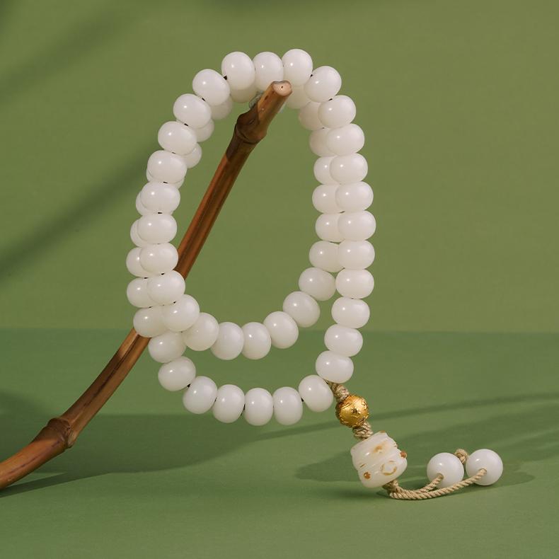 Hand-painted white Bodhi seed bracelet with cloud and snow motif, representing purity in Tibetan Buddhist jewelry art and culture.