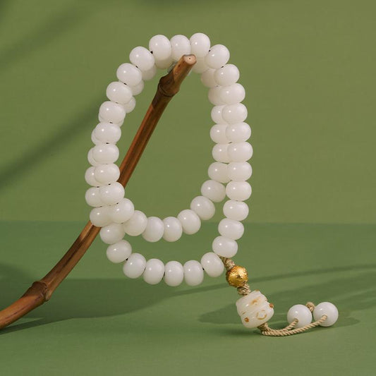 Hand-painted white Bodhi seed bracelet with cloud and snow motif, representing purity in Tibetan Buddhist jewelry art and culture.