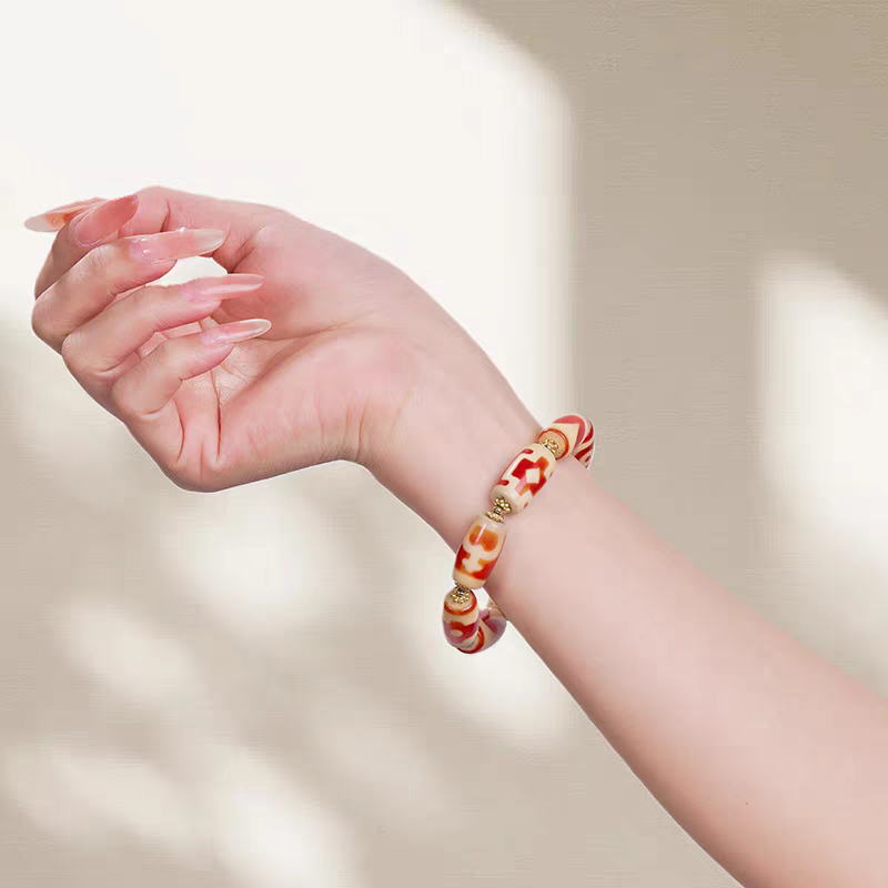 Authentic small barrel-shaped red meat agate Dzi bead bracelet, showcasing Buddhist sacrificial items art and Tibetan Buddhist sacrificial implements culture.
