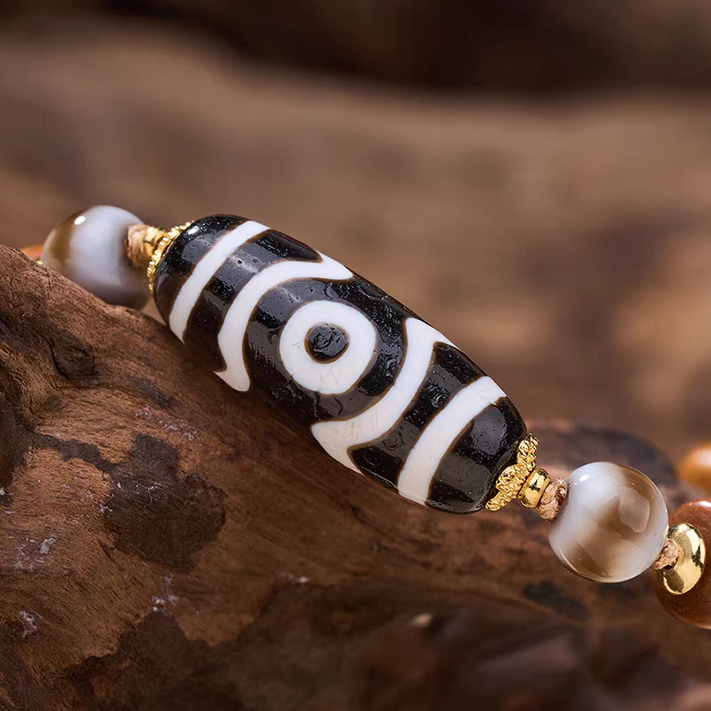 Exquisite black and white natural agate three-eyed Dzi jewelry, a spiritual artifact rooted in Tibetan Buddhist sacrificial implements culture for wealth.
