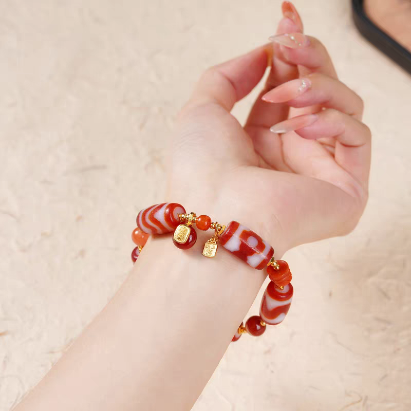 Handcrafted red Dzi bracelet with bucket beads, representing a blend of Buddhist sacrificial items art and ancient Tibetan traditions.