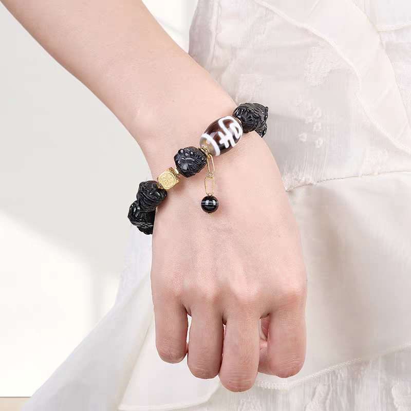 Handcrafted Tibetan Dzi bead jewelry with black Jambhala (Black Wealth God) totem, showcasing traditional Buddhist sacrificial items art and Tibetan Buddhist sacrificial implements culture.