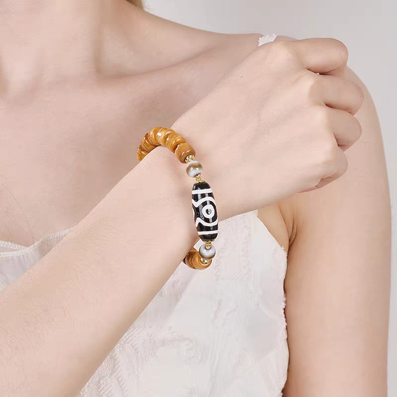 Handcrafted three-eyed Dzi bracelet representing fortune and protection in Buddhist sacrificial items art and ancient traditions.
