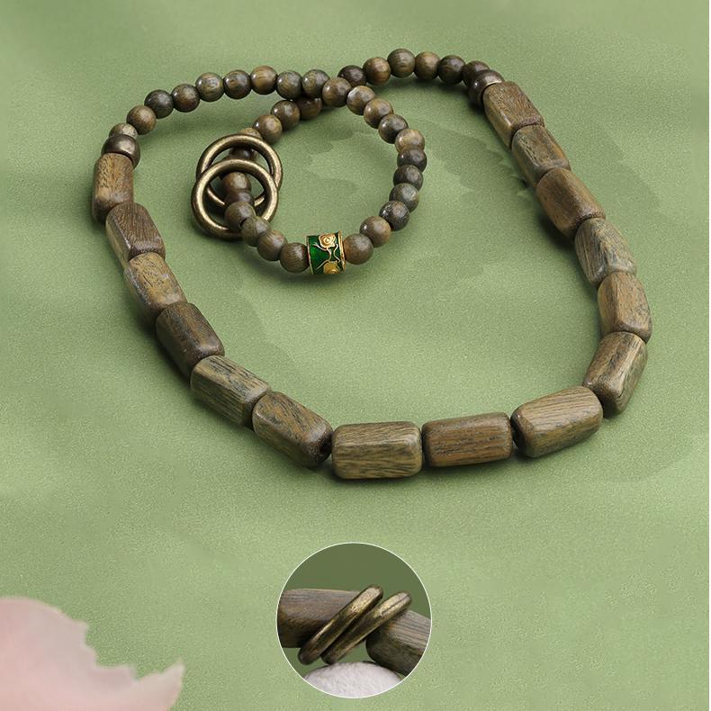 Tibetan Buddhist jewelry art showcasing a green sandalwood mala with traditional copper elements. Each hand-carved bead carries the soothing essence of a breeze's chant, created for mindful meditation.