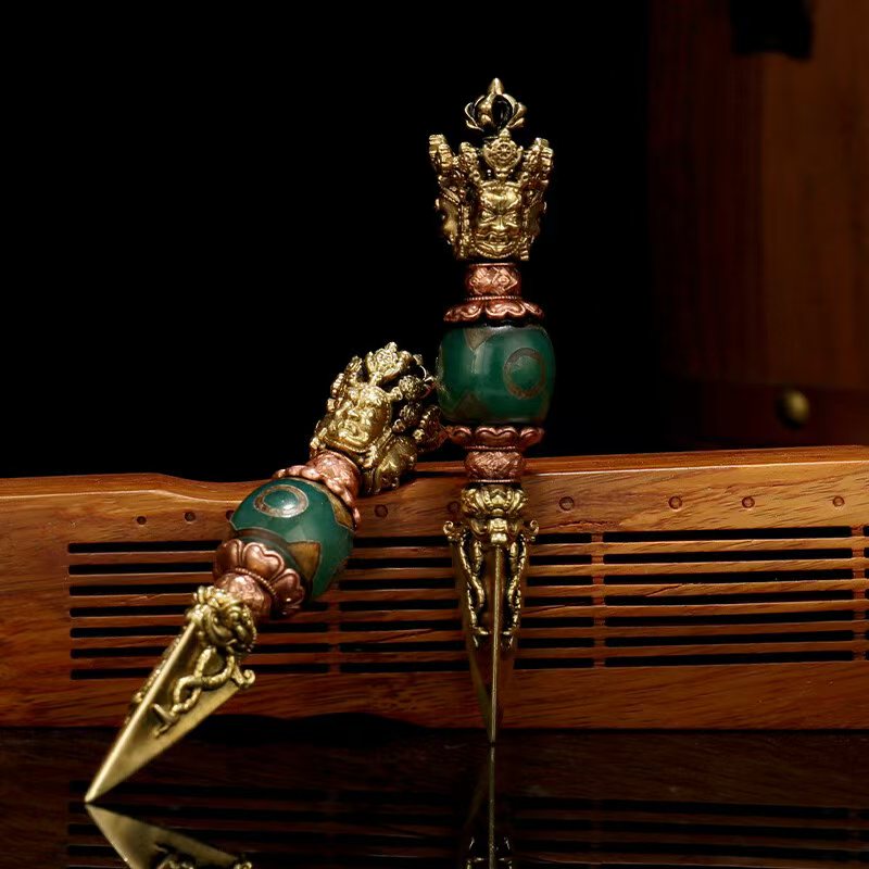 This Tibetan-style three-sided brass Phurba is meticulously handcrafted with Dzi bead accents. Symbolizing protection and spiritual strength, it is perfect for Buddhist worship or personal meditation, enhancing the sanctity and energy of any space.