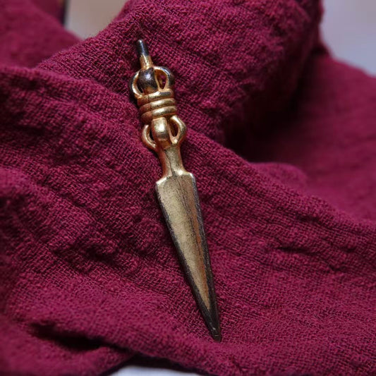 This traditional Tibetan brass Phurba, with a gilded finish, is a portable ritual tool used in Tibetan Buddhism. Handcrafted for spiritual use, it enhances meditation, protection, and spiritual rituals.