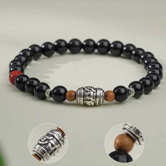 Handmade Tibetan Buddhist black obsidian bracelet with spiritual symbols, crafted for healing and protection. Jewelry art for mindful living.