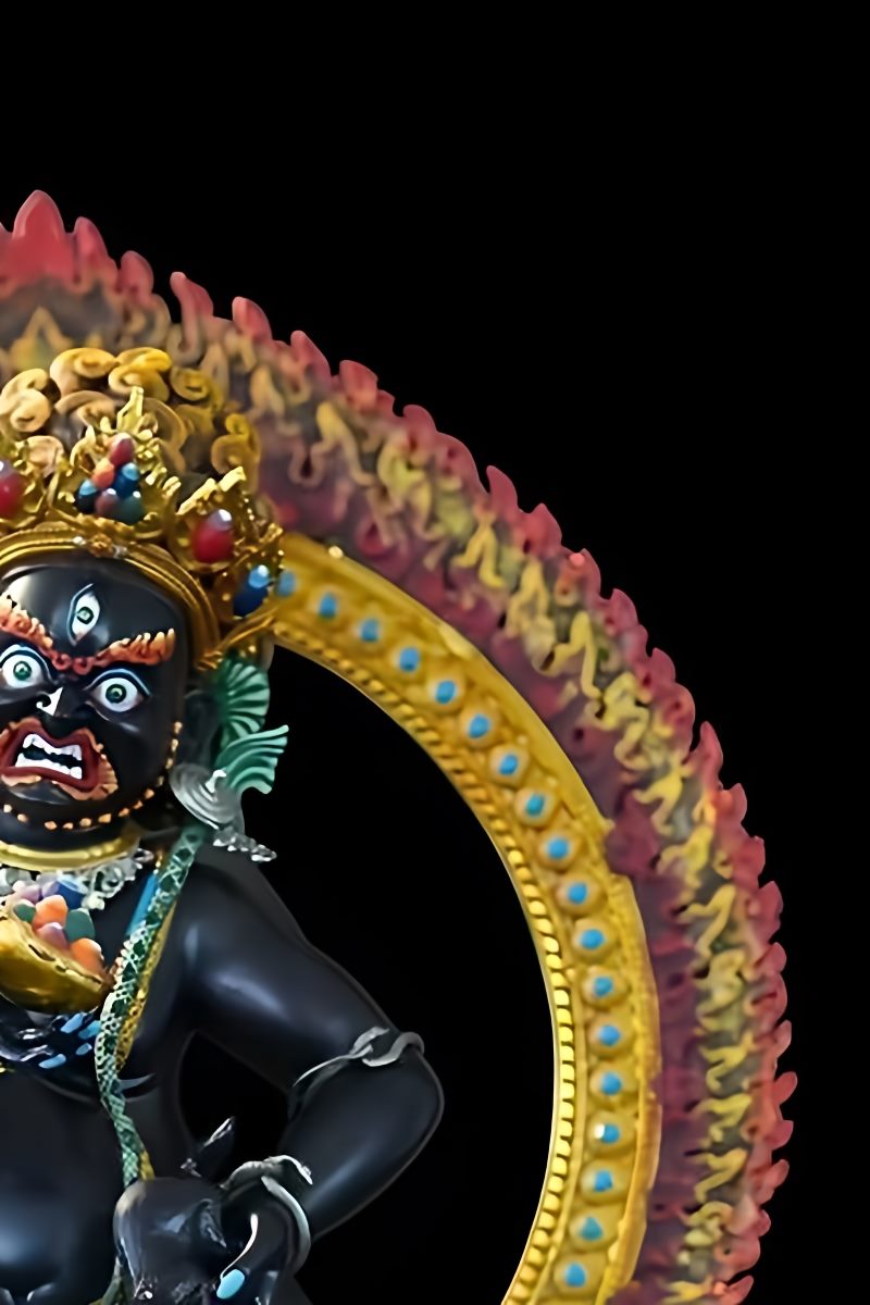 Close-up detail of a Black Jambhala Buddhist statue, highlighting the skillful hand-painting with mineral pigments used in Tibetan Buddhist ritual art.