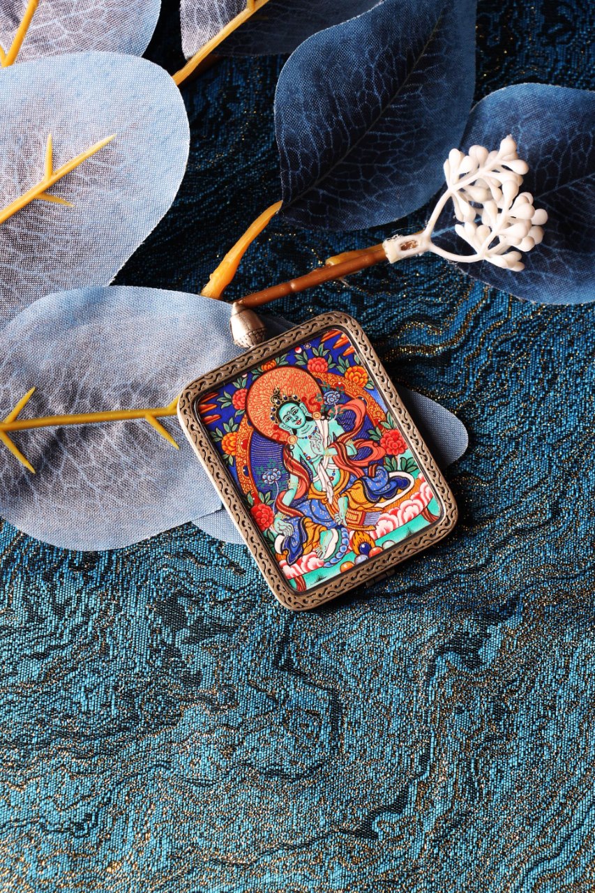 The Green Tara Thangka pendant displayed as a sacred heirloom, showcasing the exquisite Rebgong craftsmanship and silver casing.