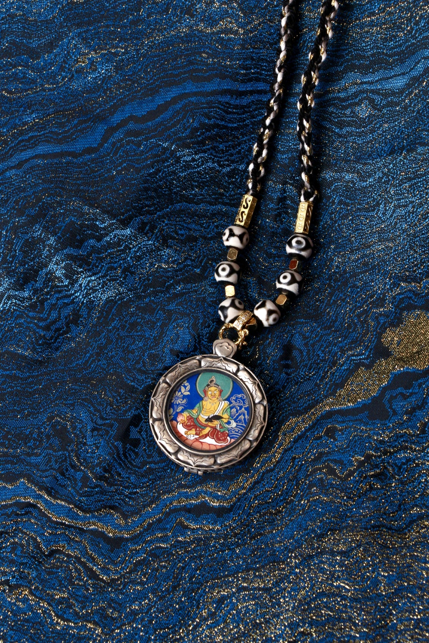 Macro view of the 2.5cm Kurukulla Thangka showing the vibrant red mineral pigments and fine lines used by Tibetan masters.