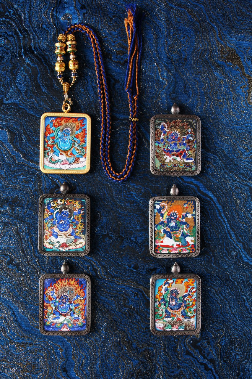 The Six-Armed Mahakala protector pendant displayed on a decorative blue textile background.