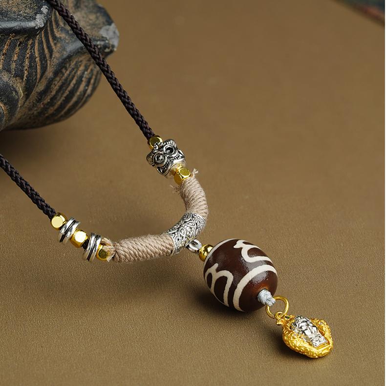 Close-up of a handcrafted agate Dzi bead in an ornate copper frame, showing traditional Tibetan artistry.