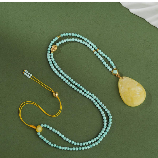 Tibetan Buddhist handcrafted amber pendant with 925 silver and turquoise, expressing calm and purity.