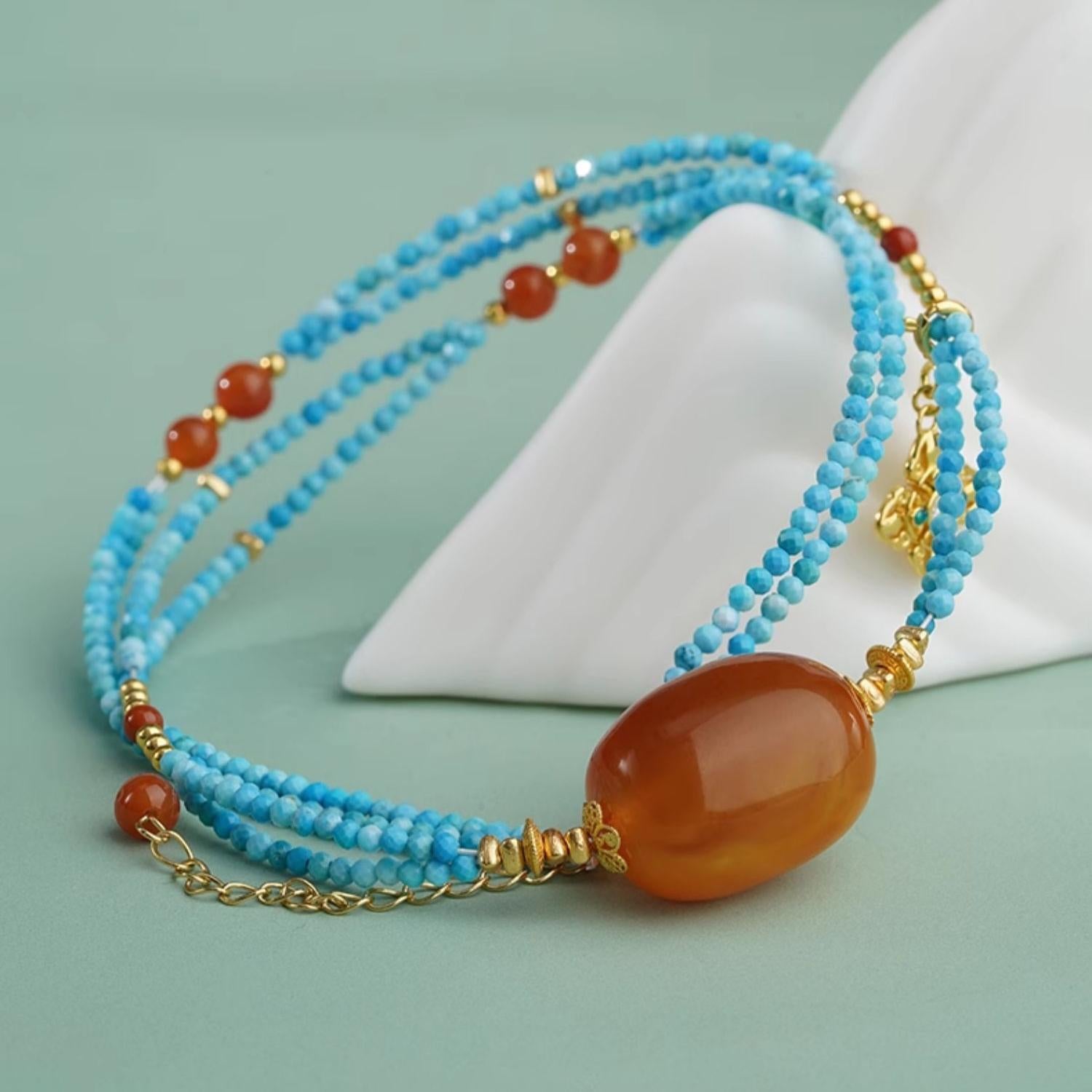 Handmade amber and red agate necklace with turquoise beads, inspired by Tibetan Buddhist art.