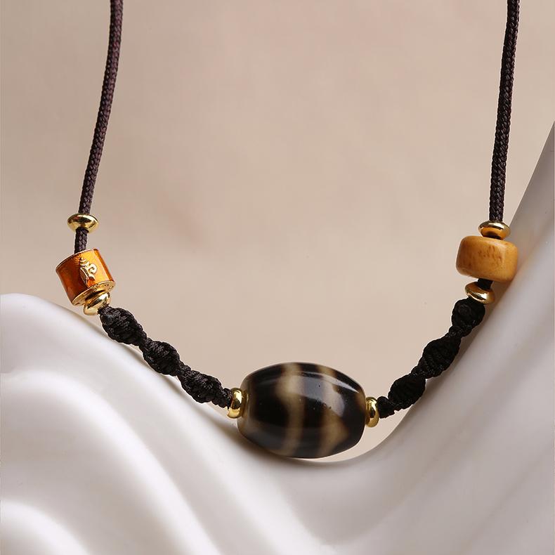 Tibetan Buddhist necklace featuring double tiger tooth Dzi bead and carved bone accents.
