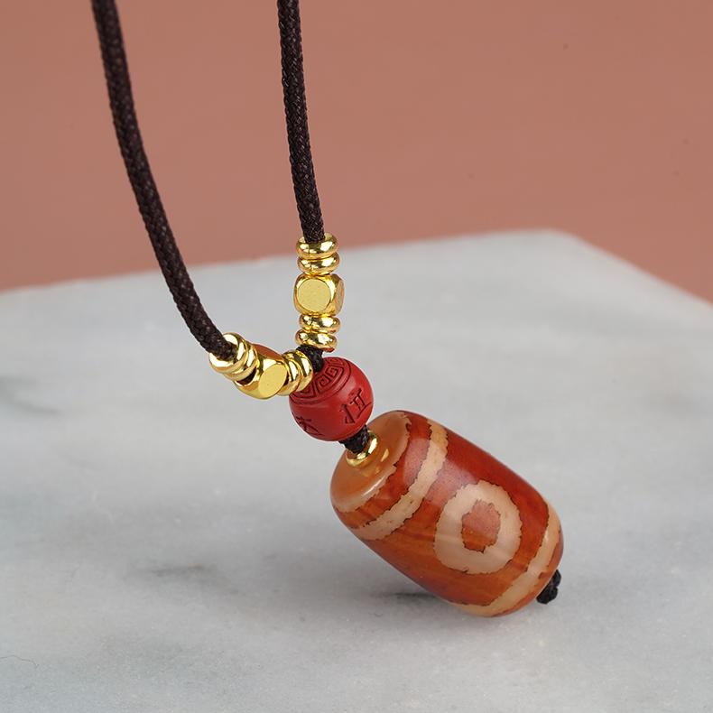 Powerful protection amulet featuring a single eye Dzi bead with cinnabar details for spiritual backing.